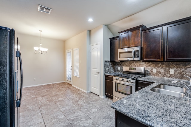 kitchen with sink, appliances with stainless steel finishes, light stone countertops, a notable chandelier, and decorative backsplash