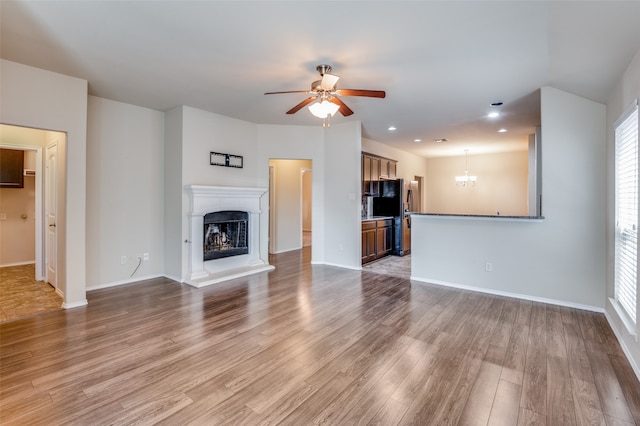 unfurnished living room featuring hardwood / wood-style flooring and ceiling fan with notable chandelier