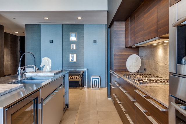 kitchen featuring wine cooler, appliances with stainless steel finishes, light tile patterned floors, decorative backsplash, and sink