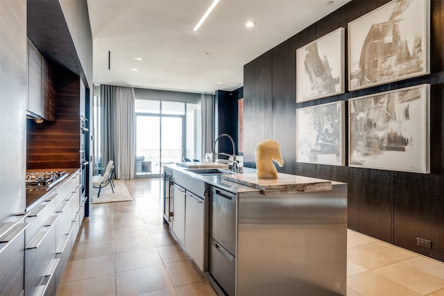 kitchen with light tile patterned flooring, sink, an island with sink, stainless steel gas stovetop, and white cabinets