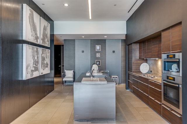 kitchen featuring sink, an island with sink, light tile patterned flooring, and stainless steel appliances