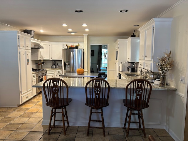 kitchen featuring stainless steel appliances, white cabinetry, light stone countertops, and kitchen peninsula