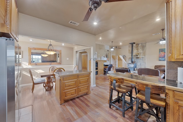 kitchen with backsplash, pendant lighting, stainless steel refrigerator, and light hardwood / wood-style flooring