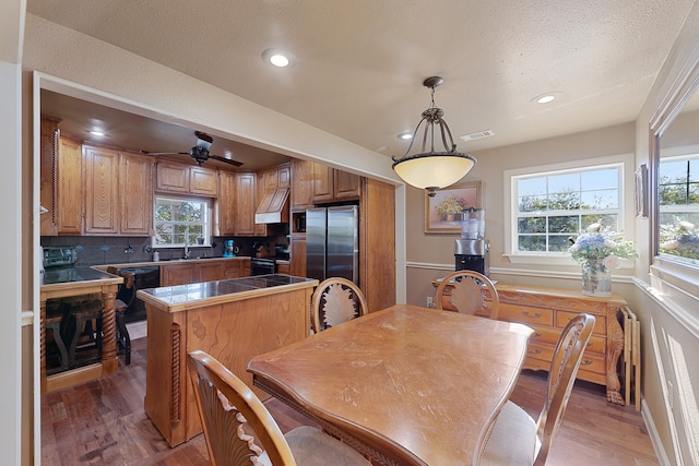 kitchen with stainless steel appliances, wood-type flooring, pendant lighting, and decorative backsplash