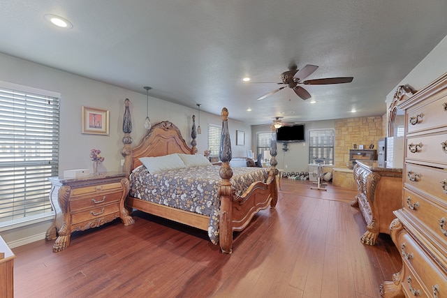 bedroom with a textured ceiling, dark hardwood / wood-style flooring, and ceiling fan