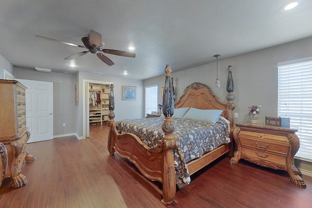 bedroom featuring dark wood-type flooring, a spacious closet, and ceiling fan