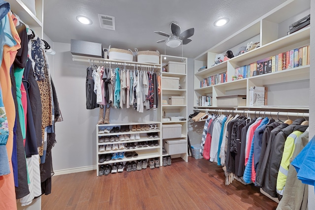 spacious closet with dark wood-type flooring and ceiling fan