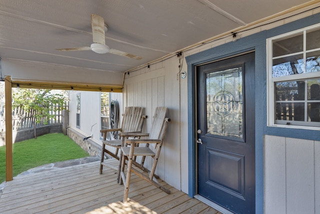 view of exterior entry with ceiling fan and a wooden deck