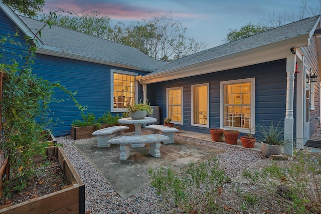 back house at dusk with a patio area