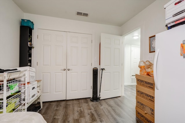 bedroom featuring a closet, wood-type flooring, and white fridge