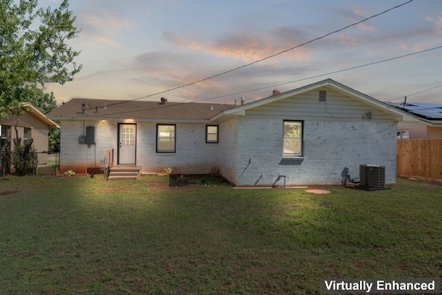 back house at dusk with central AC and a yard