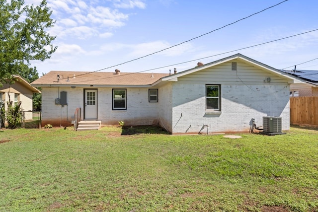 rear view of house featuring central AC unit and a lawn