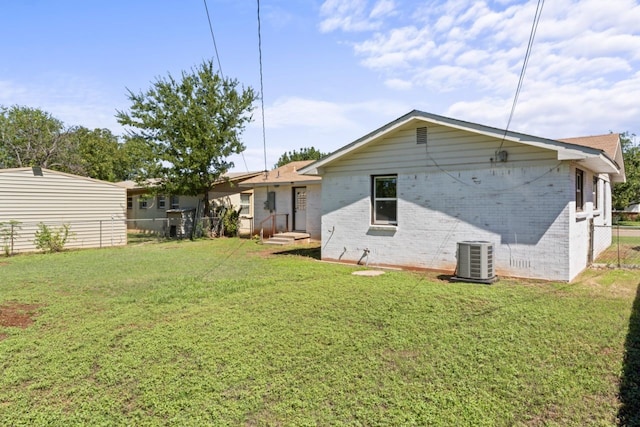 rear view of property with cooling unit and a lawn