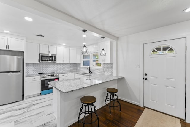 kitchen with kitchen peninsula, white cabinetry, plenty of natural light, and appliances with stainless steel finishes