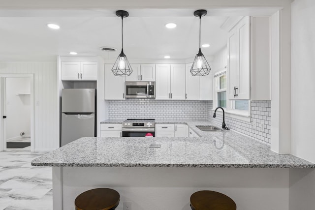 kitchen featuring sink, a breakfast bar area, white cabinetry, appliances with stainless steel finishes, and decorative light fixtures