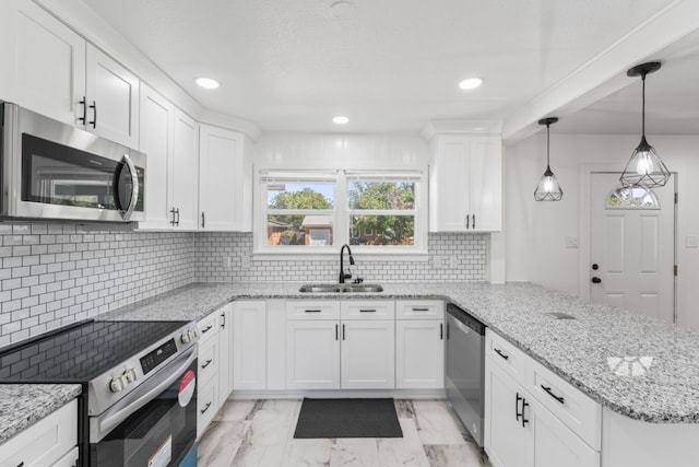 kitchen featuring kitchen peninsula, sink, white cabinetry, appliances with stainless steel finishes, and decorative light fixtures