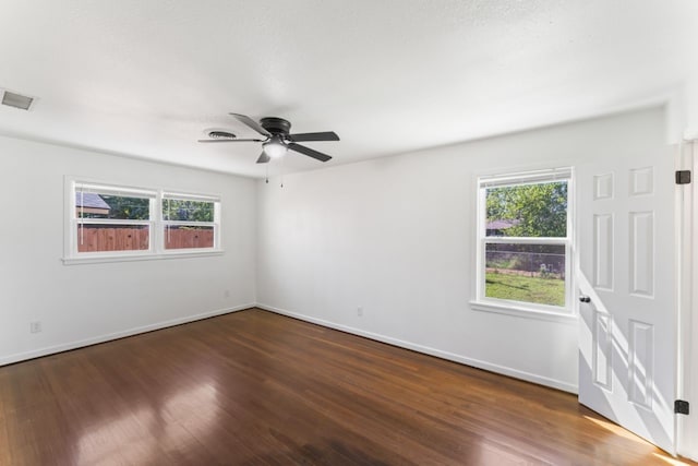 unfurnished room featuring a wealth of natural light, ceiling fan, and dark hardwood / wood-style flooring