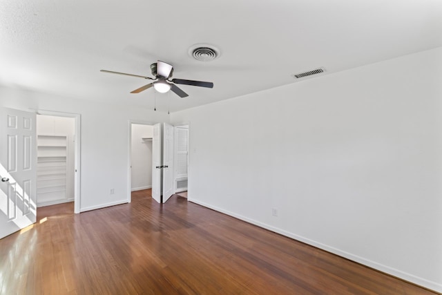 unfurnished bedroom with ceiling fan, dark hardwood / wood-style floors, a closet, and a spacious closet