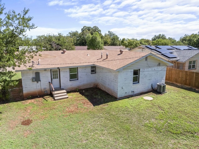 back of house with central AC unit and a yard