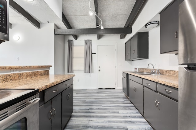 kitchen with a textured ceiling, light wood-type flooring, sink, and beam ceiling