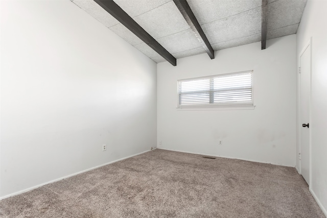 spare room featuring carpet flooring and vaulted ceiling with beams