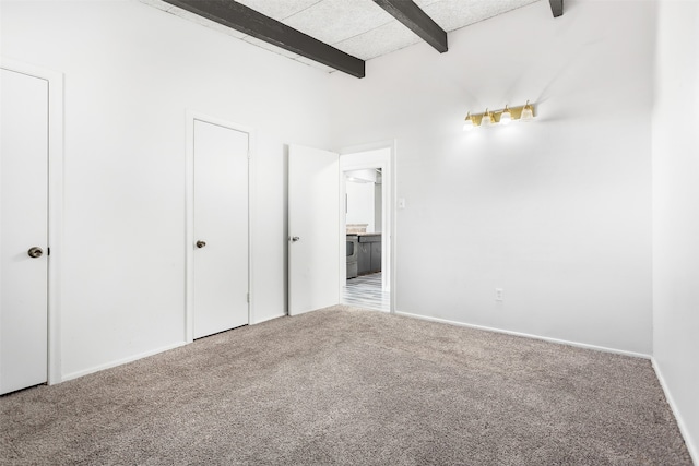 unfurnished bedroom featuring beam ceiling and light carpet