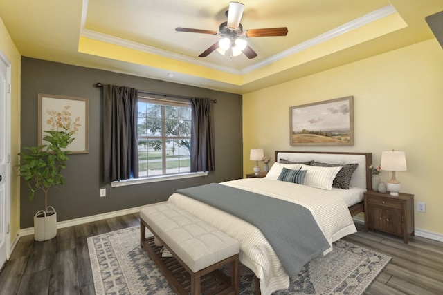 bedroom with ornamental molding, dark wood-type flooring, ceiling fan, and a raised ceiling