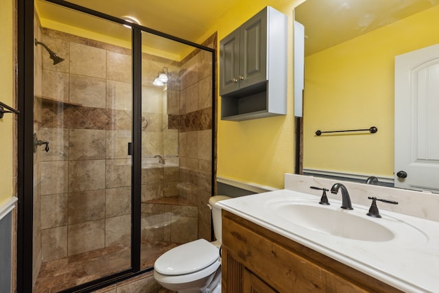 bathroom featuring toilet, vanity, and a shower with door