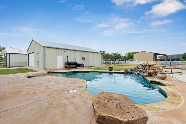 view of swimming pool featuring a garage, an outbuilding, and pool water feature