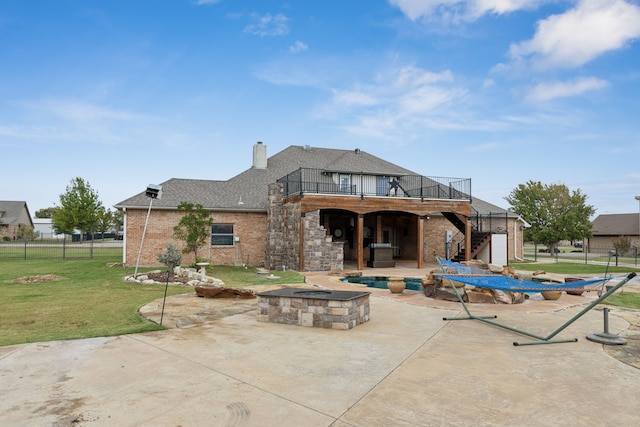 rear view of property featuring a patio, a yard, and a fire pit