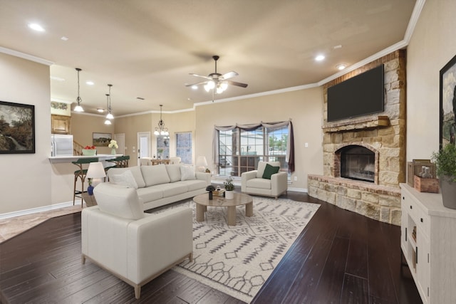 living room featuring dark hardwood / wood-style flooring, ceiling fan, a stone fireplace, and ornamental molding