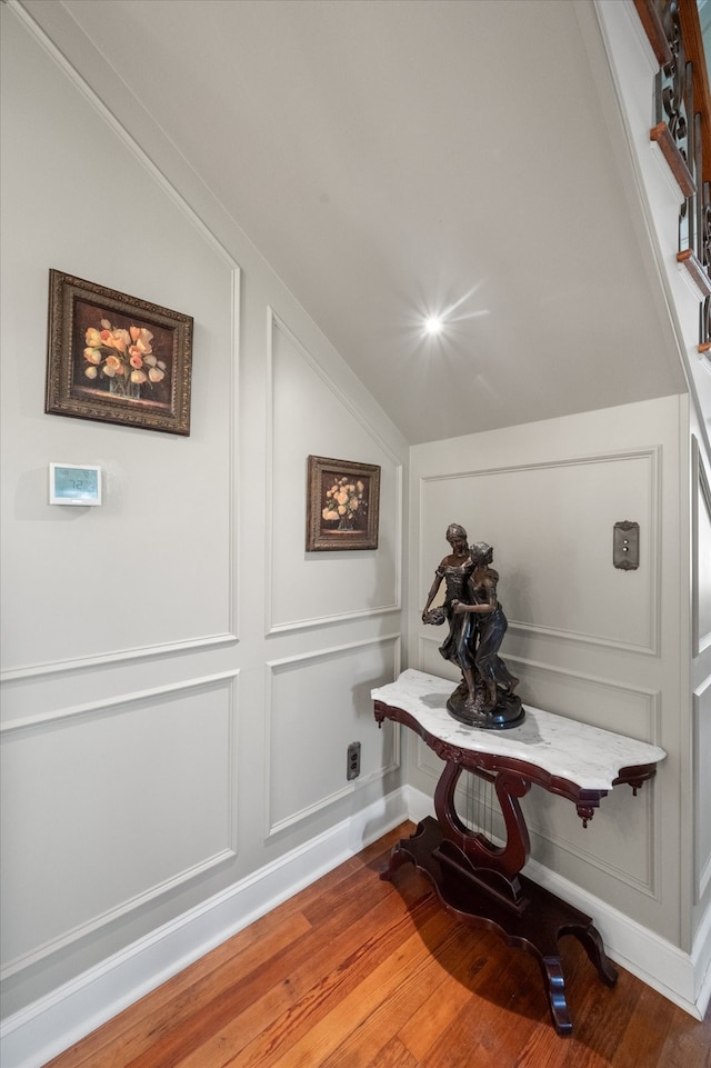 corridor with hardwood / wood-style floors and lofted ceiling