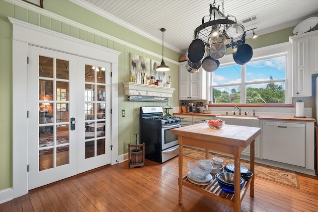 kitchen featuring french doors, dishwasher, stainless steel gas stove, white cabinetry, and hanging light fixtures