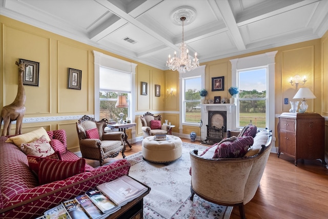 living room featuring coffered ceiling, a premium fireplace, light hardwood / wood-style flooring, beamed ceiling, and a notable chandelier