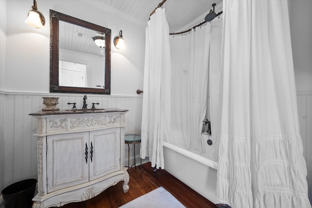 bathroom with ornamental molding, vanity, wooden walls, shower / bathtub combination with curtain, and hardwood / wood-style floors