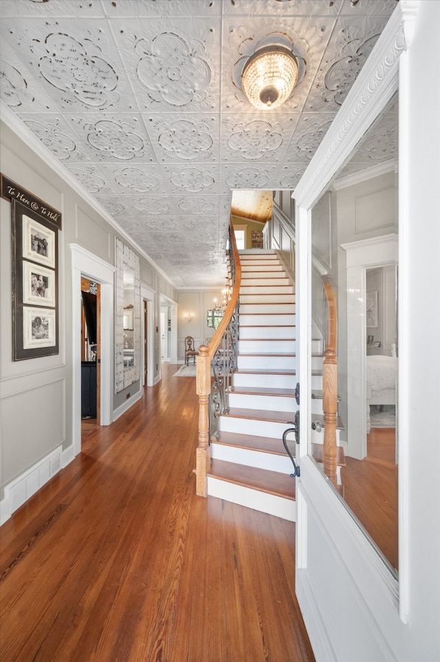 stairway with hardwood / wood-style flooring and crown molding