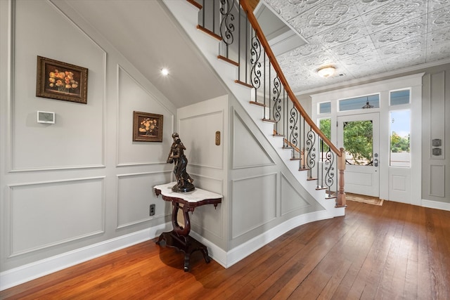 staircase featuring lofted ceiling, hardwood / wood-style flooring, and crown molding