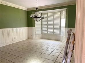 unfurnished dining area featuring light tile patterned floors, crown molding, and an inviting chandelier