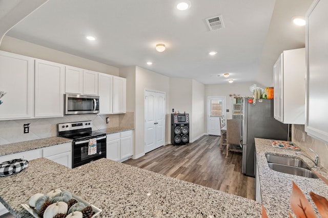 kitchen with stainless steel appliances, light wood-type flooring, light stone countertops, sink, and white cabinets