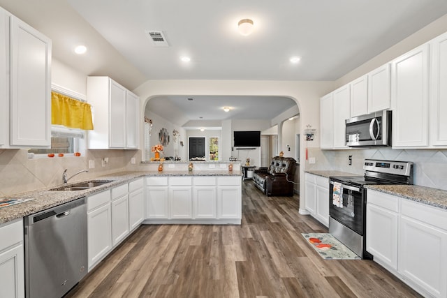 kitchen with stainless steel appliances, white cabinetry, sink, kitchen peninsula, and dark hardwood / wood-style flooring