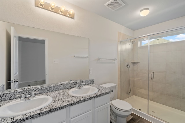 bathroom featuring toilet, vanity, hardwood / wood-style flooring, and a shower with door