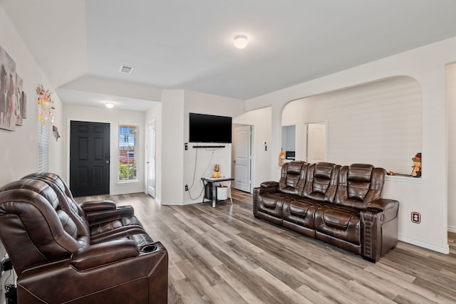 living room with light hardwood / wood-style floors and vaulted ceiling