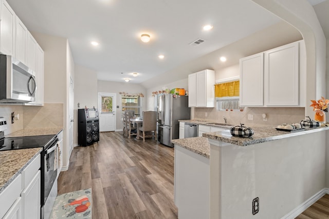 kitchen featuring white cabinets, light wood-type flooring, stainless steel appliances, and light stone counters