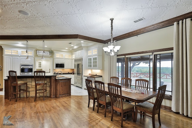 dining room featuring ornamental molding, an inviting chandelier, and light hardwood / wood-style floors