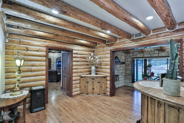 interior space featuring beamed ceiling, rustic walls, wood-type flooring, and a fireplace