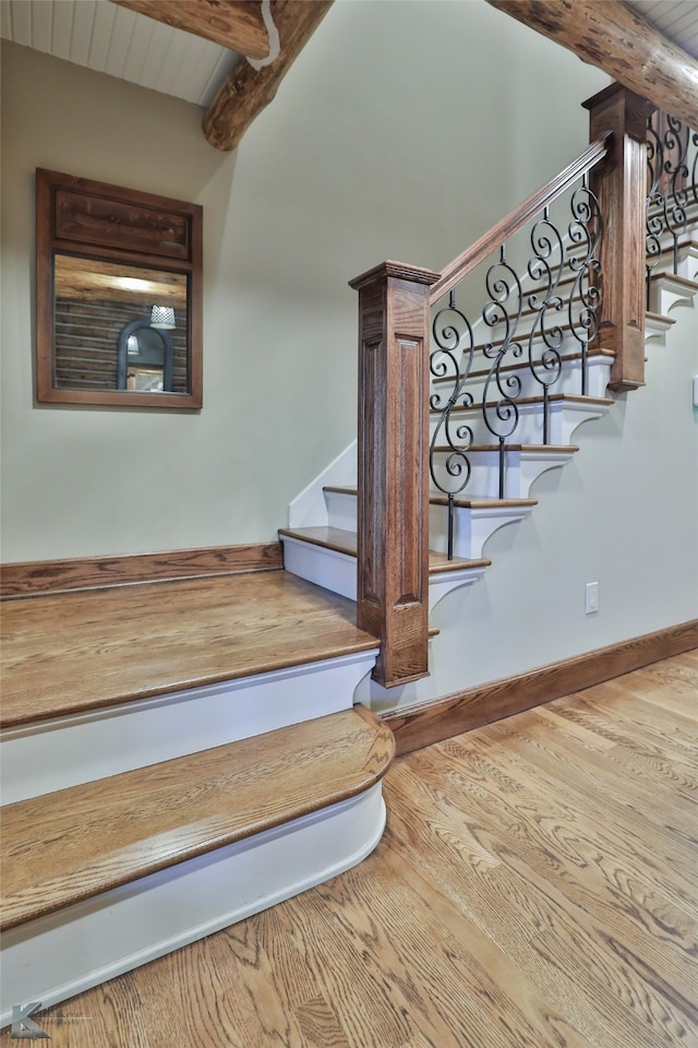 stairs featuring wooden ceiling, hardwood / wood-style flooring, and beam ceiling