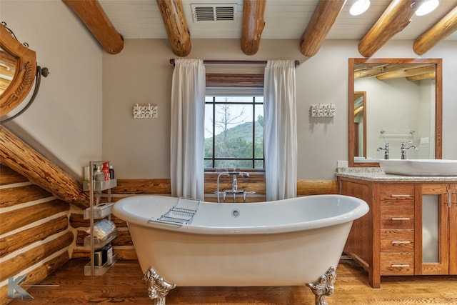 bathroom with beam ceiling, vanity, hardwood / wood-style flooring, and a bathing tub