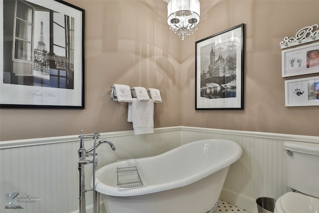 bathroom featuring tile patterned floors, toilet, a bathtub, and a notable chandelier