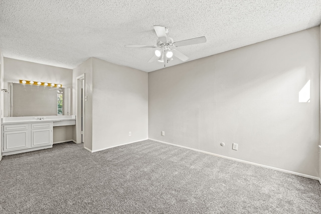 unfurnished bedroom featuring carpet flooring, built in desk, a textured ceiling, and ceiling fan