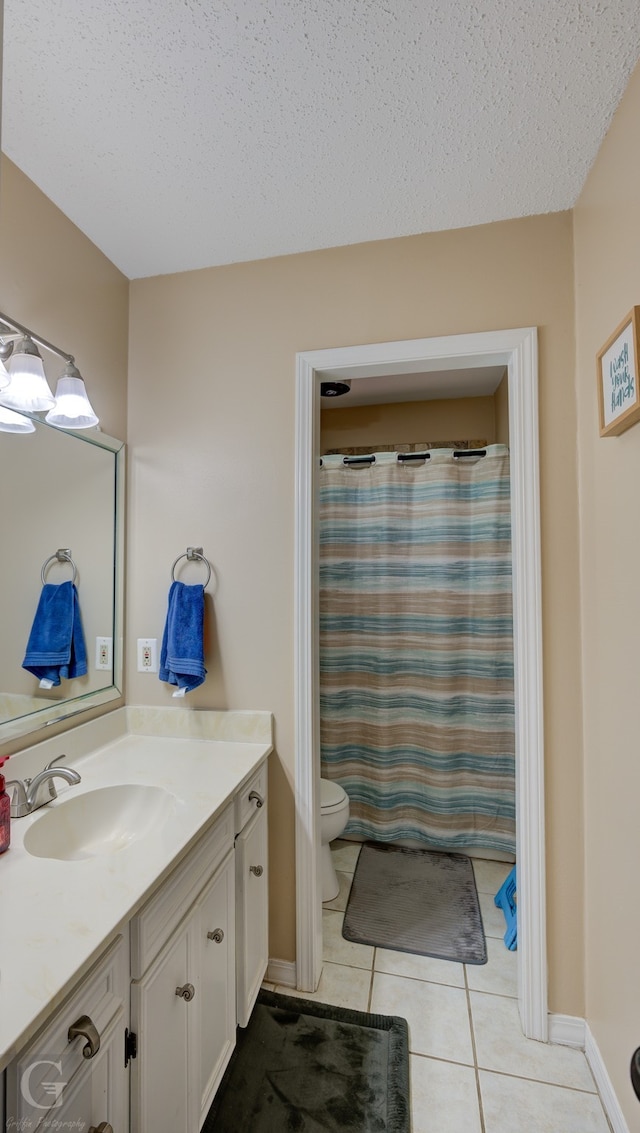 bathroom with walk in shower, vanity, a textured ceiling, tile patterned flooring, and toilet